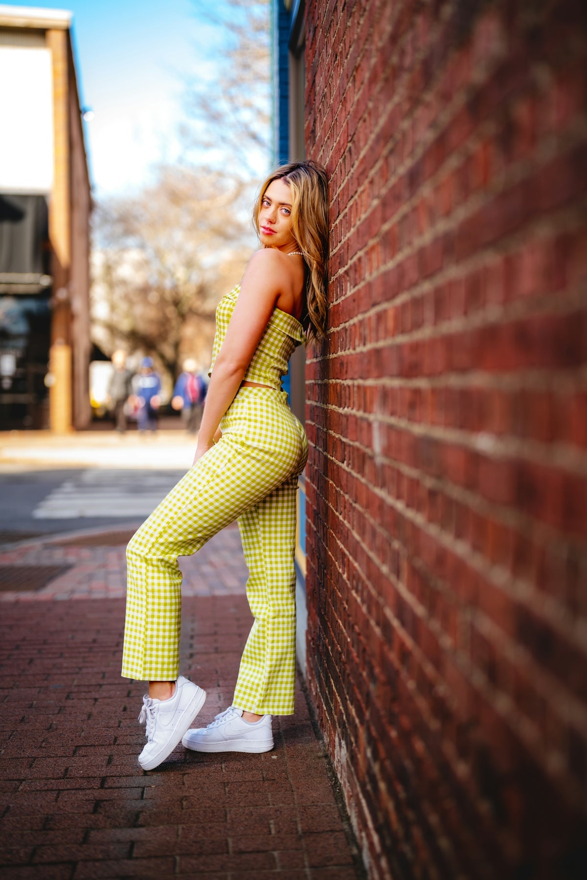 a woman leaning against a brick wall