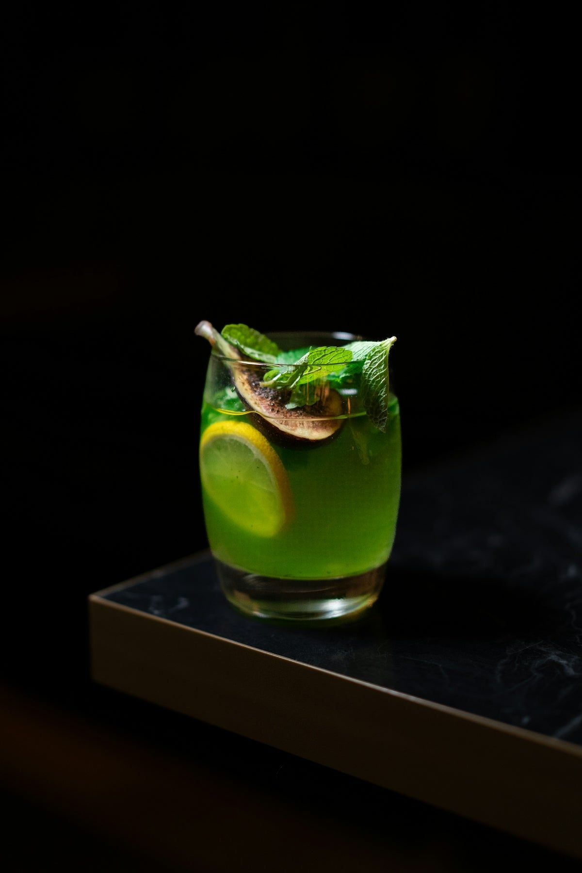 a green drink with a slice of lemon and mint