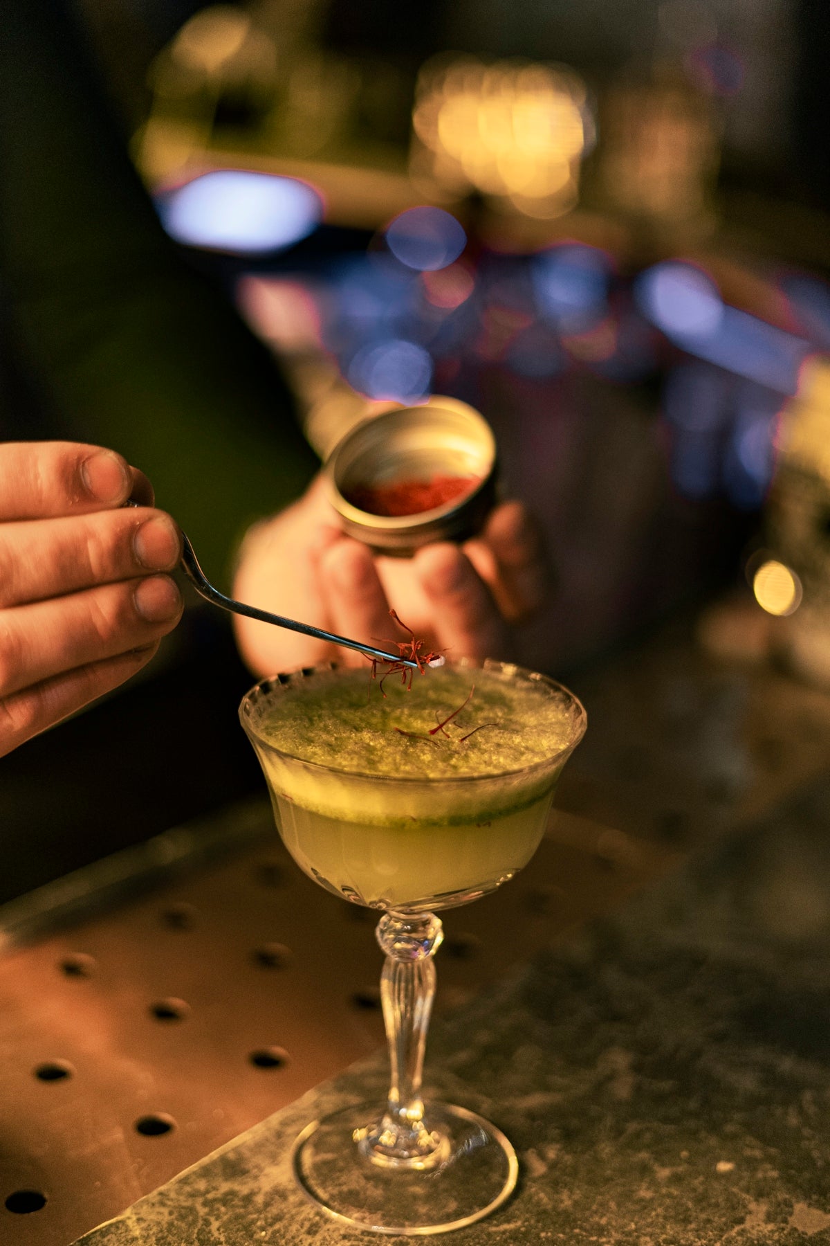 a person is holding a spoon over a martini