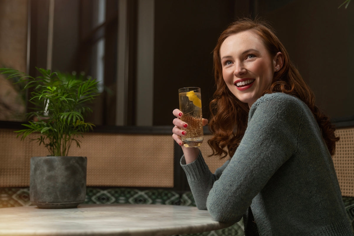 a woman sitting at a table holding a glass of wine