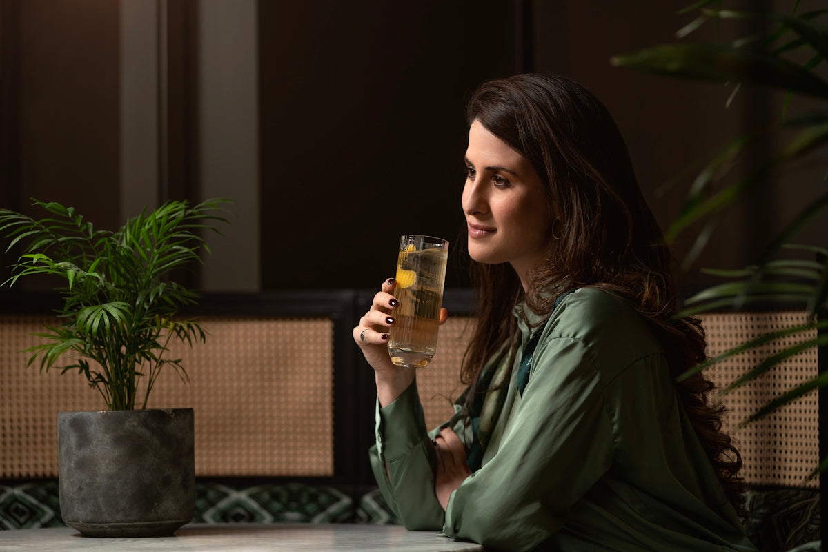 a woman sitting at a table holding a glass of wine