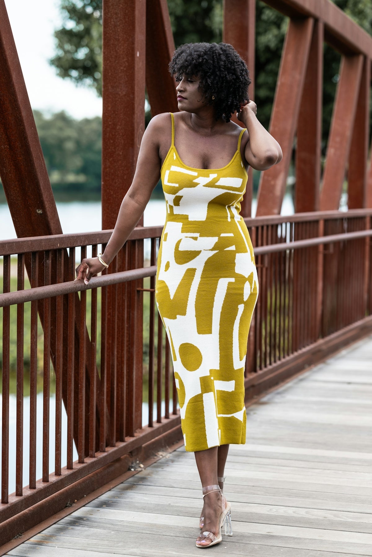 a woman in a yellow and white dress walking across a bridge