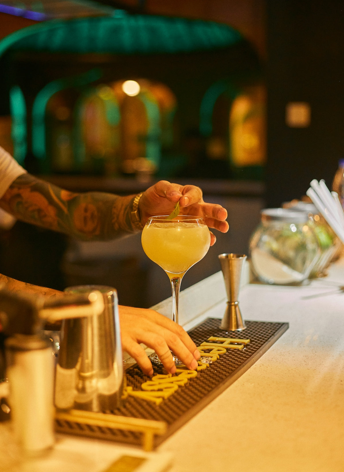 Bartender garnishing a cocktail with a lime wedge.