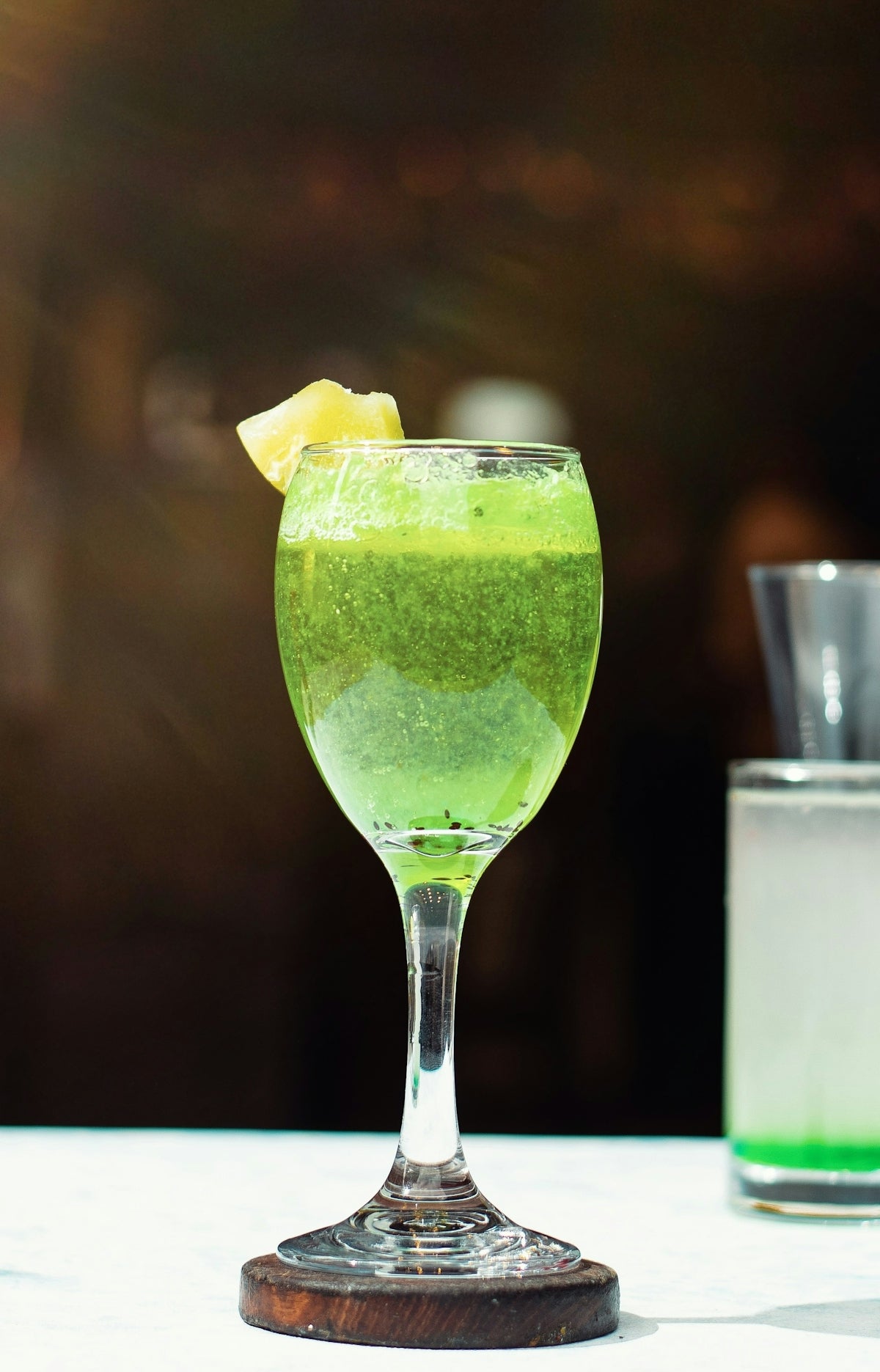 a green drink with a slice of lemon on the rim