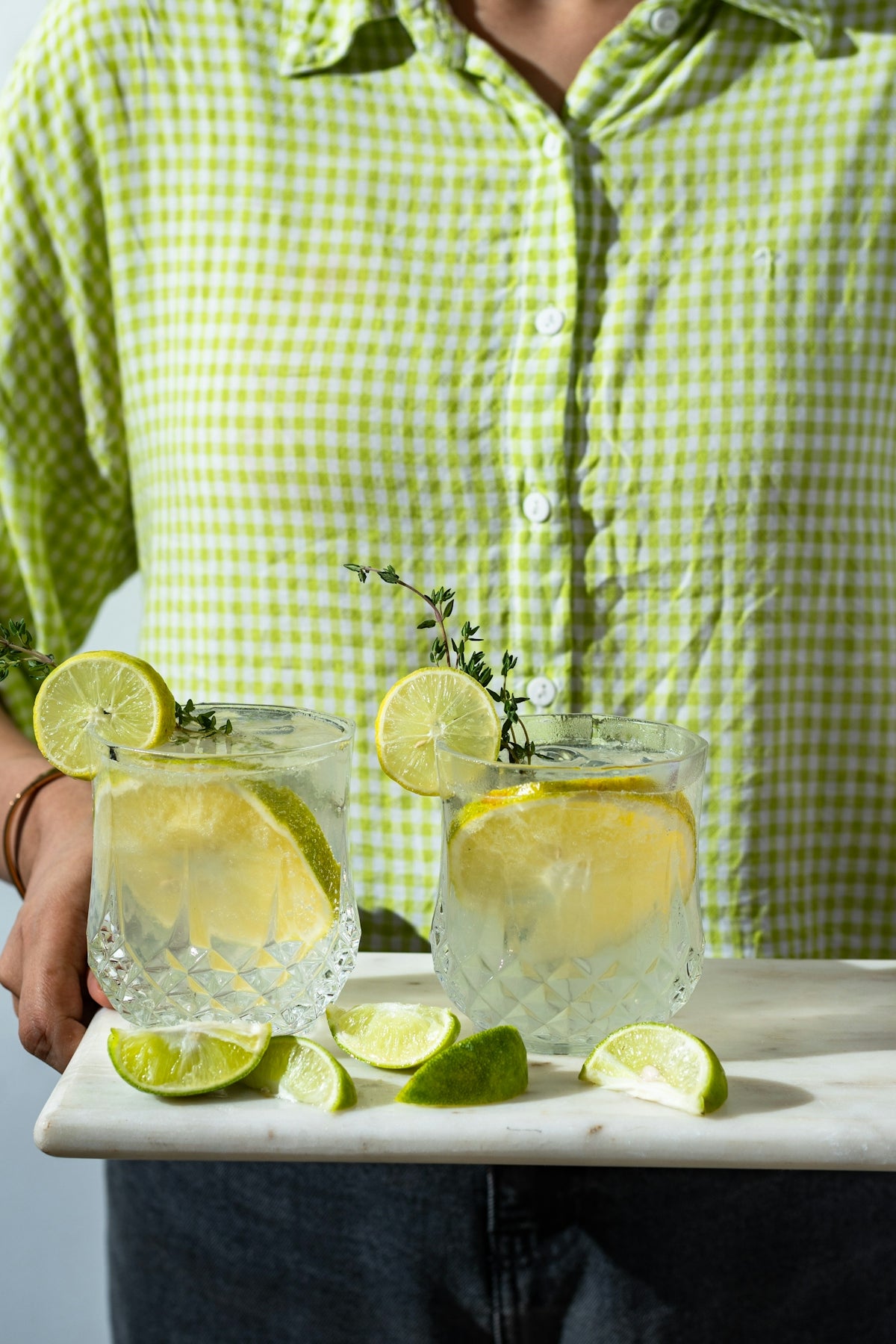 a man holding a tray with two glasses of lemonade