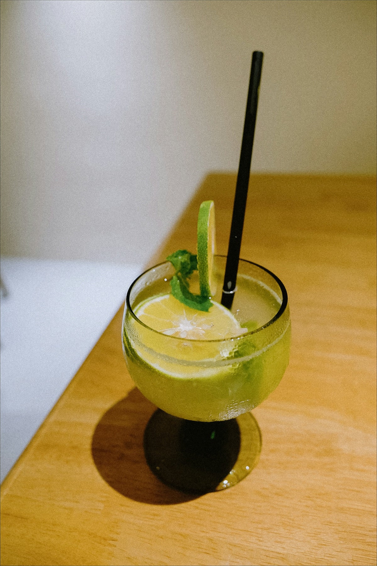 A green drink with a black straw in a glass