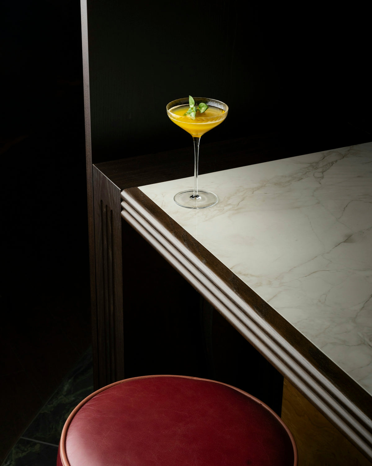 A cocktail sitting on top of a table next to a stool