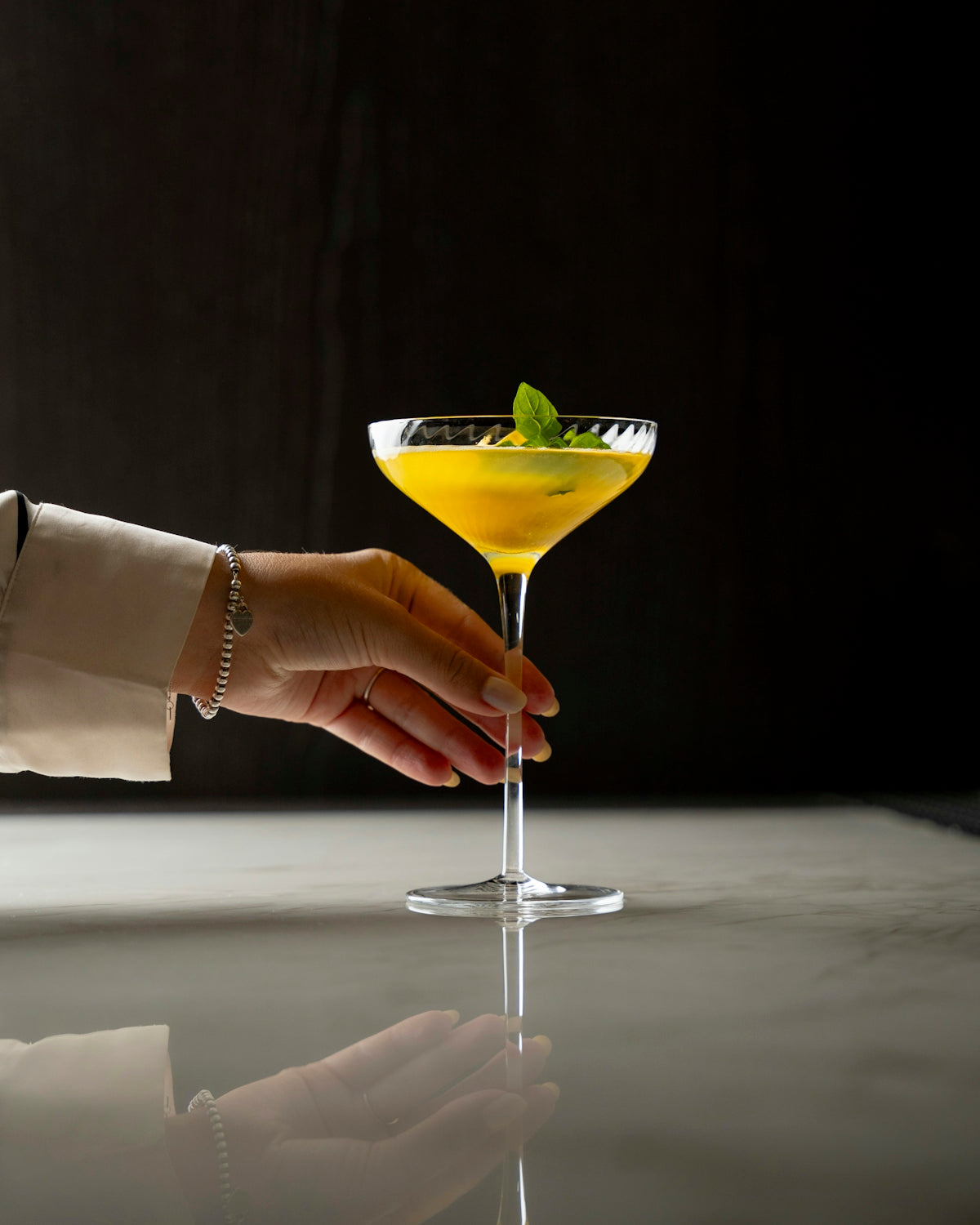 A hand reaching for a drink in a martini glass
