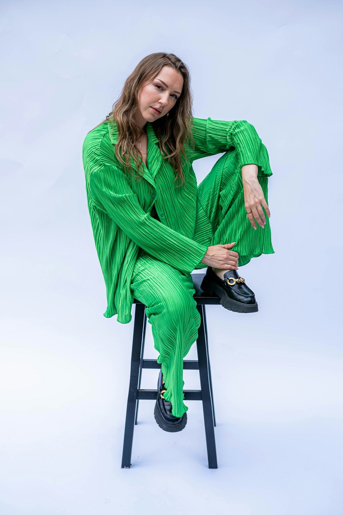 A woman sitting on a stool in a green outfit