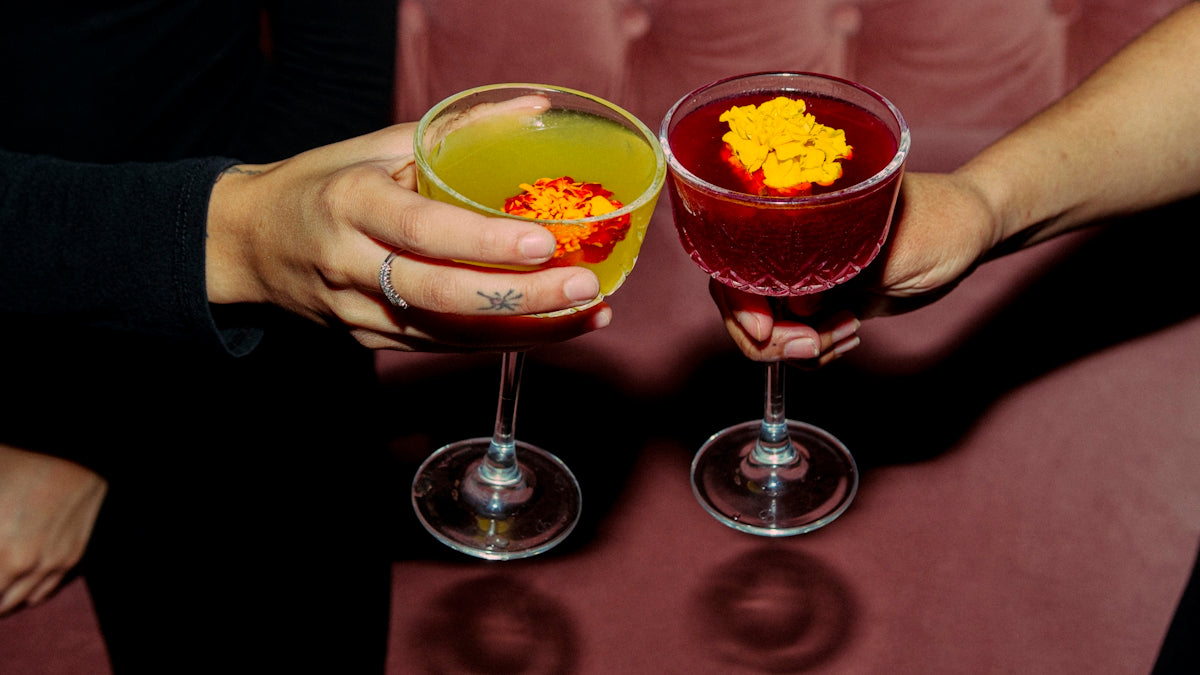 Two people cheers with colorful cocktails.