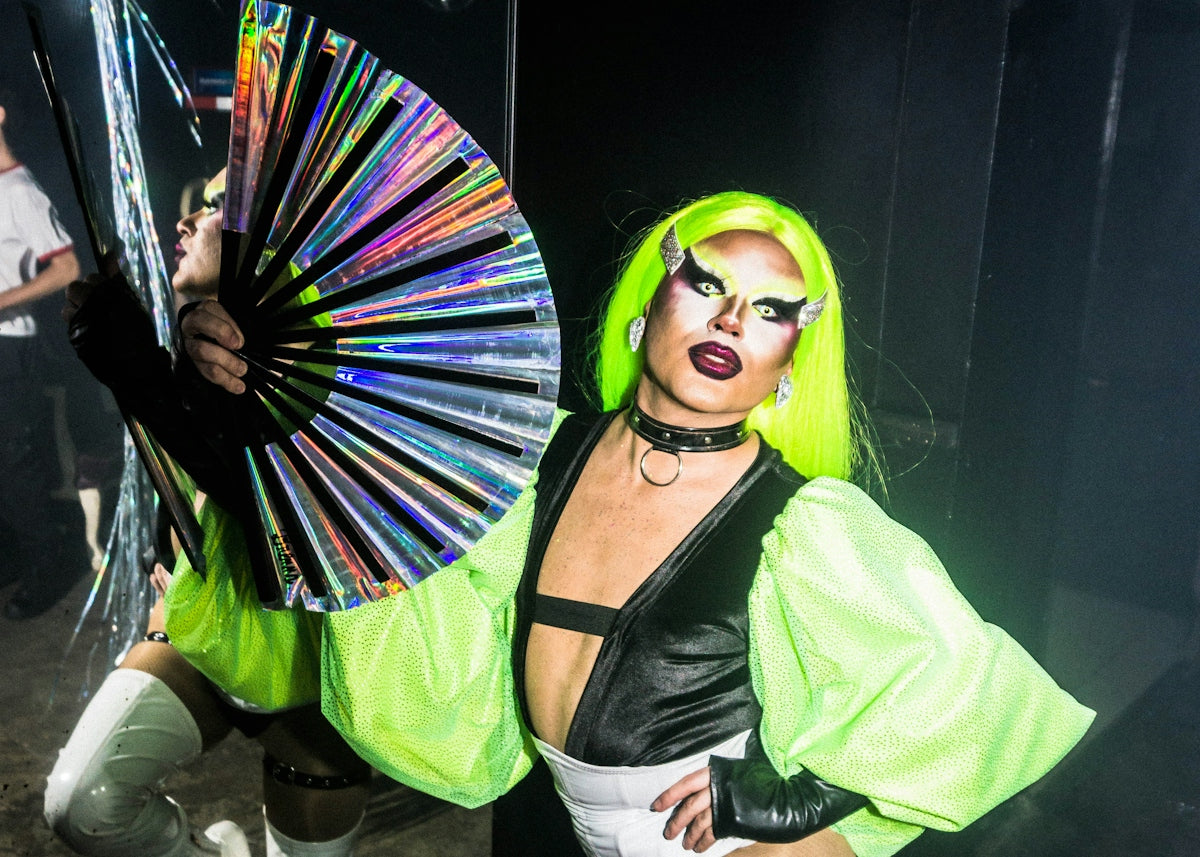 A drag queen poses with a fan