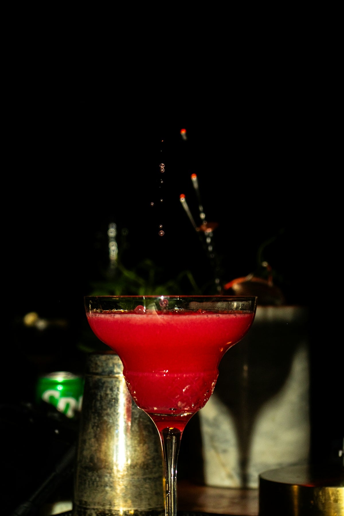 A bright, pink cocktail is being poured.