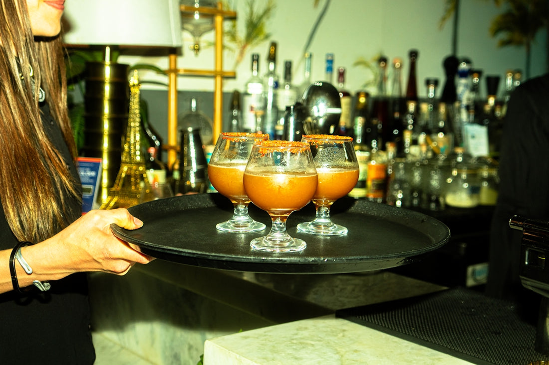 A waitress carries cocktails on a tray.