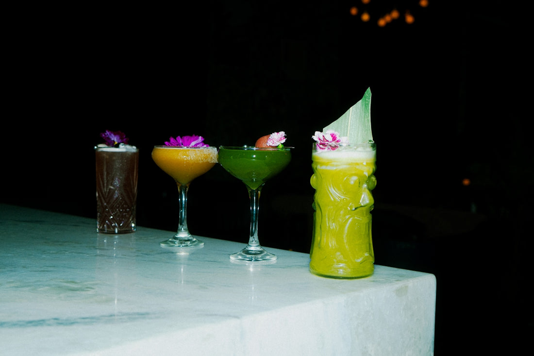 Cocktails with flowers are arranged on a bar.