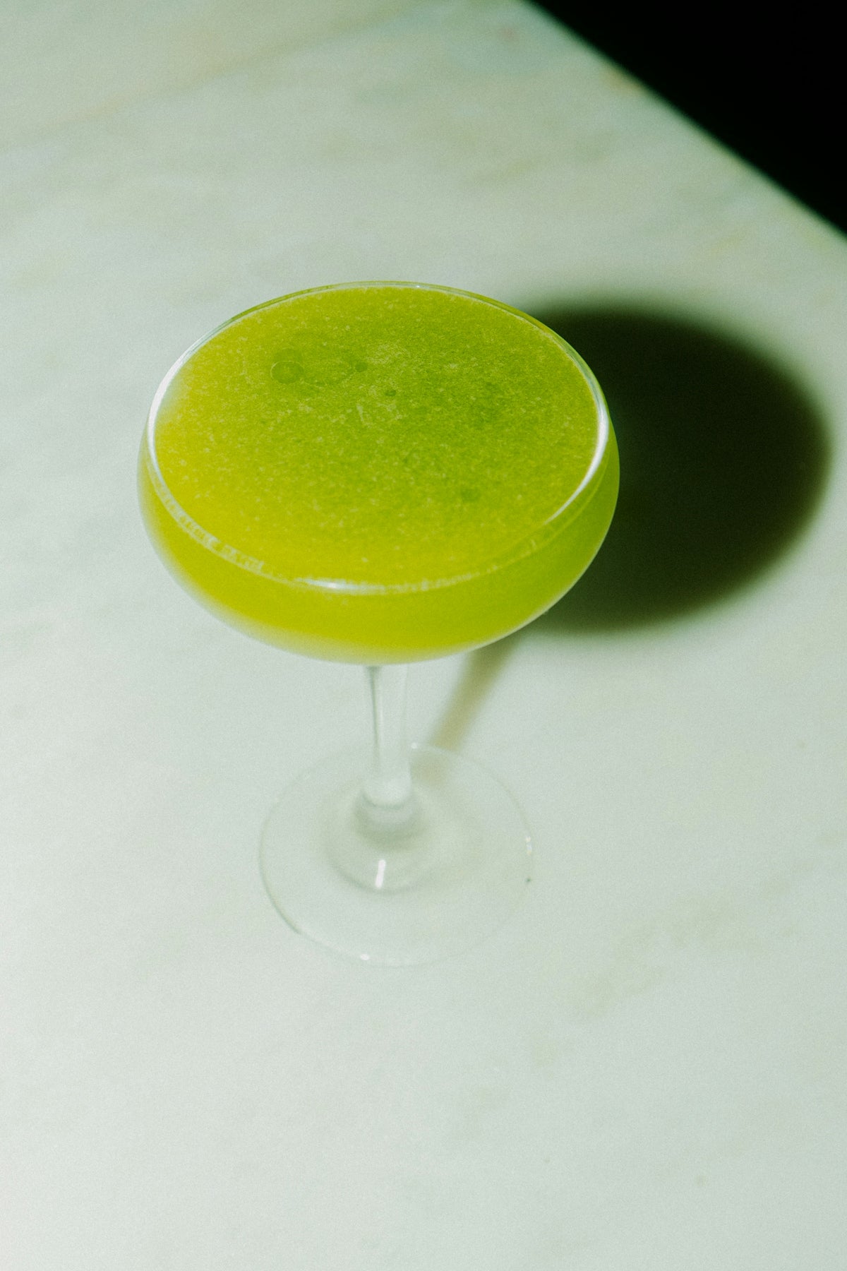 A green cocktail in a sleek glass.