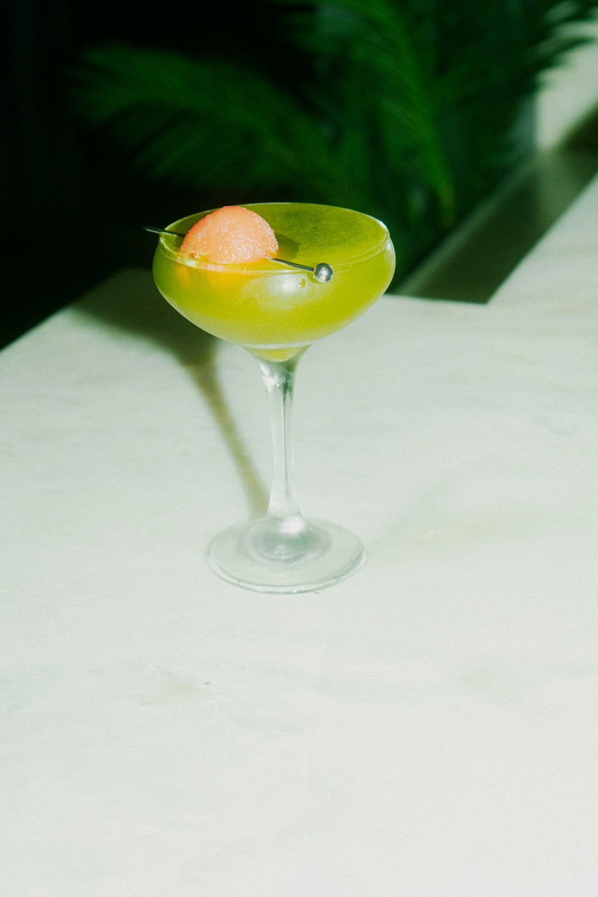 A green cocktail with a fruity garnish.