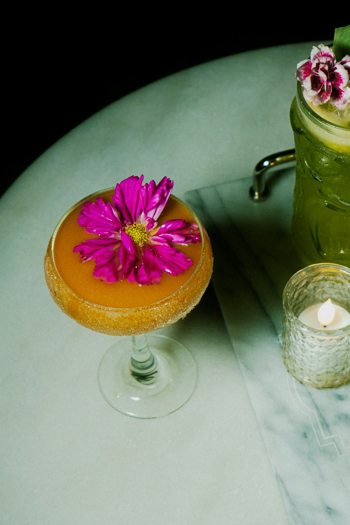Floral cocktails adorn a marble table.