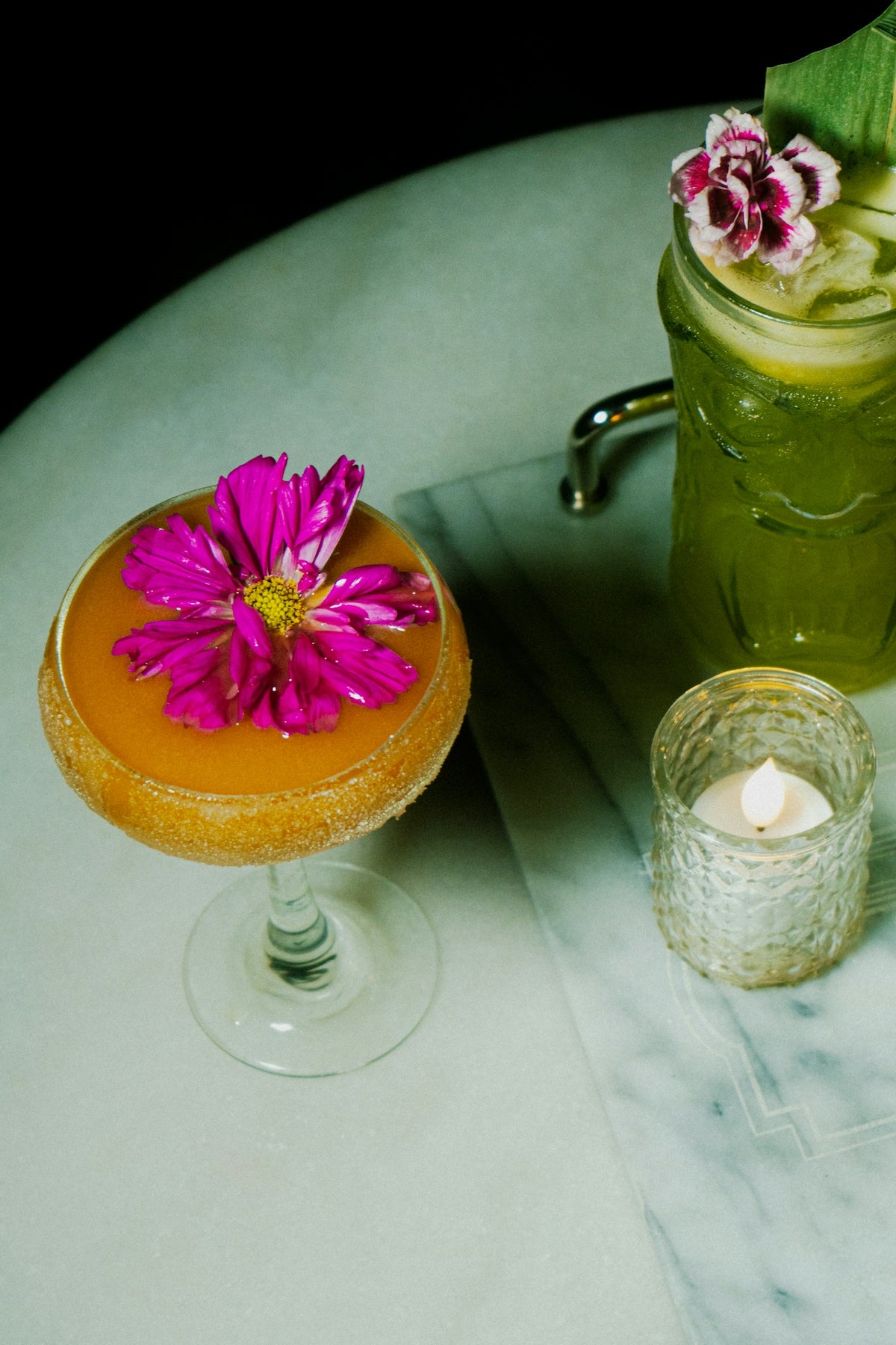 Delicious cocktails garnished with fresh flowers and a candle.