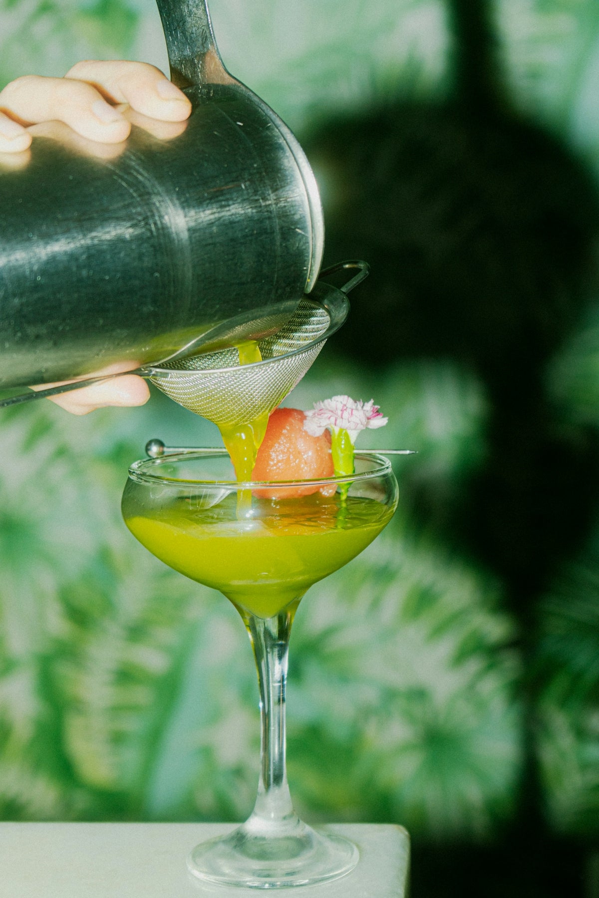 A cocktail is being poured into a decorated glass.