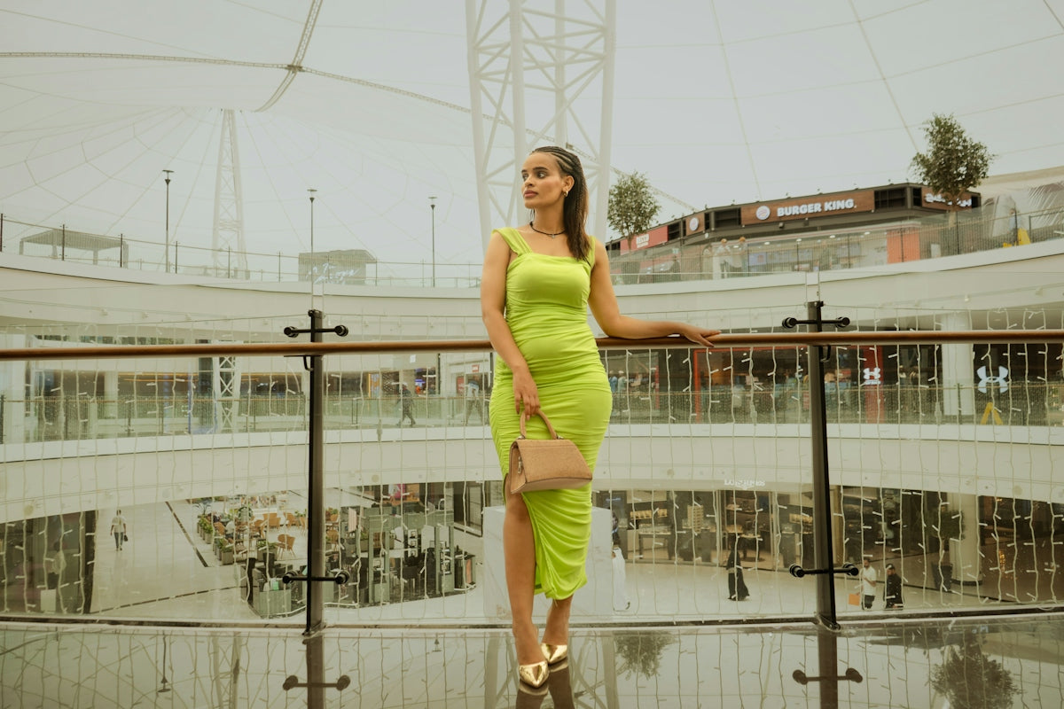 A woman poses in a stylish green dress.