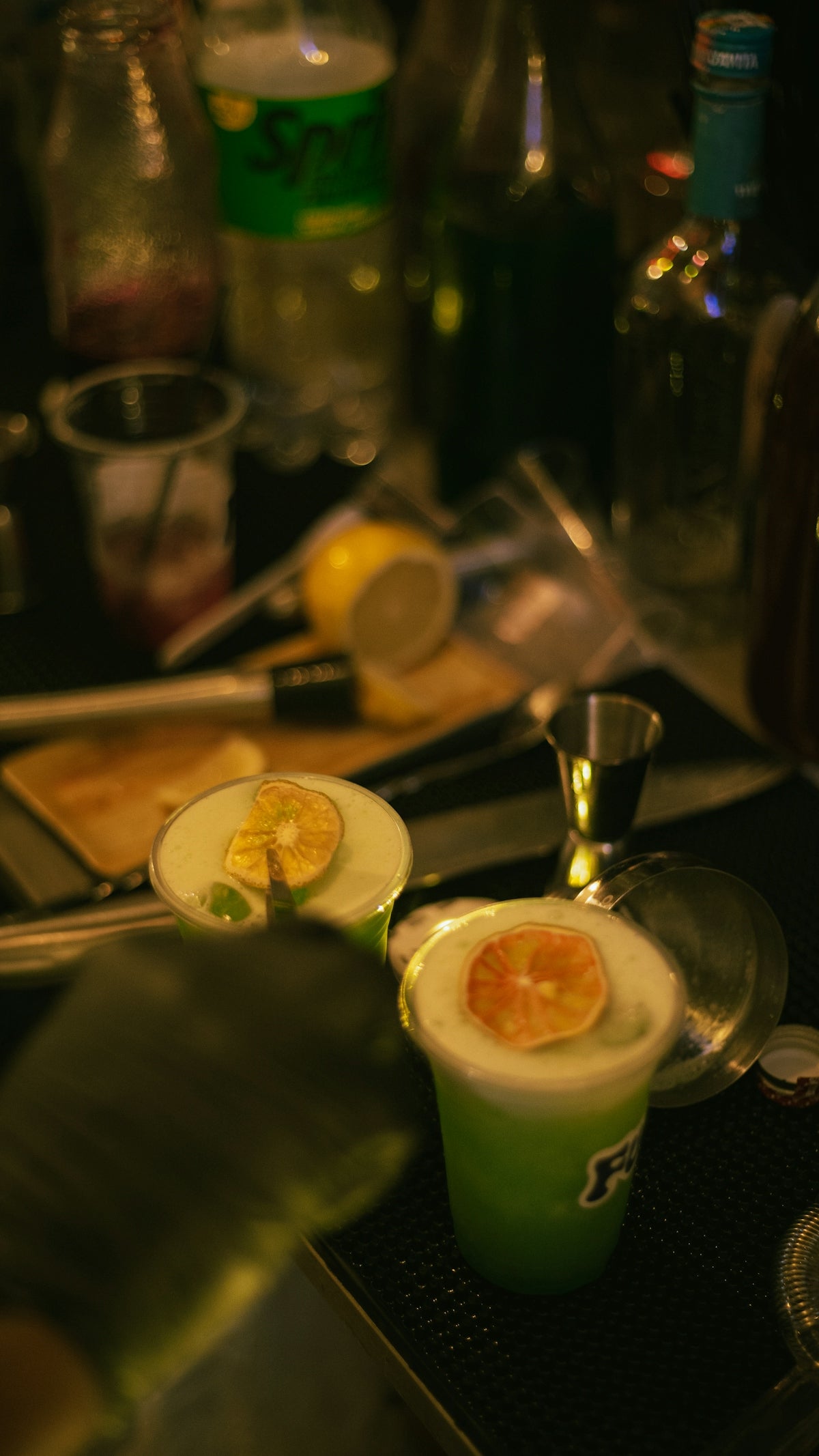 Two green cocktails with orange slices.