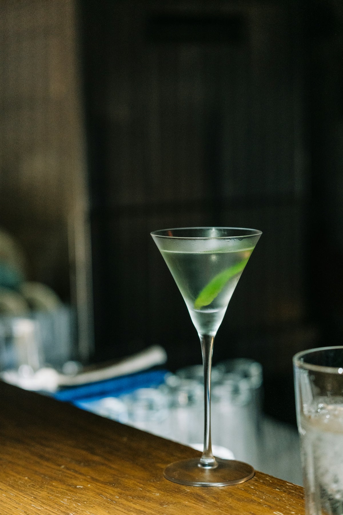 A martini glass sits on a wooden bar.