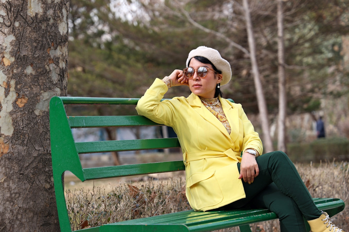 Woman in yellow jacket sits on a park bench