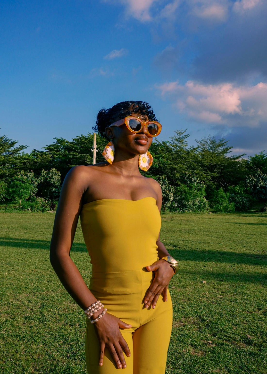 Woman in yellow jumpsuit with heart sunglasses outdoors