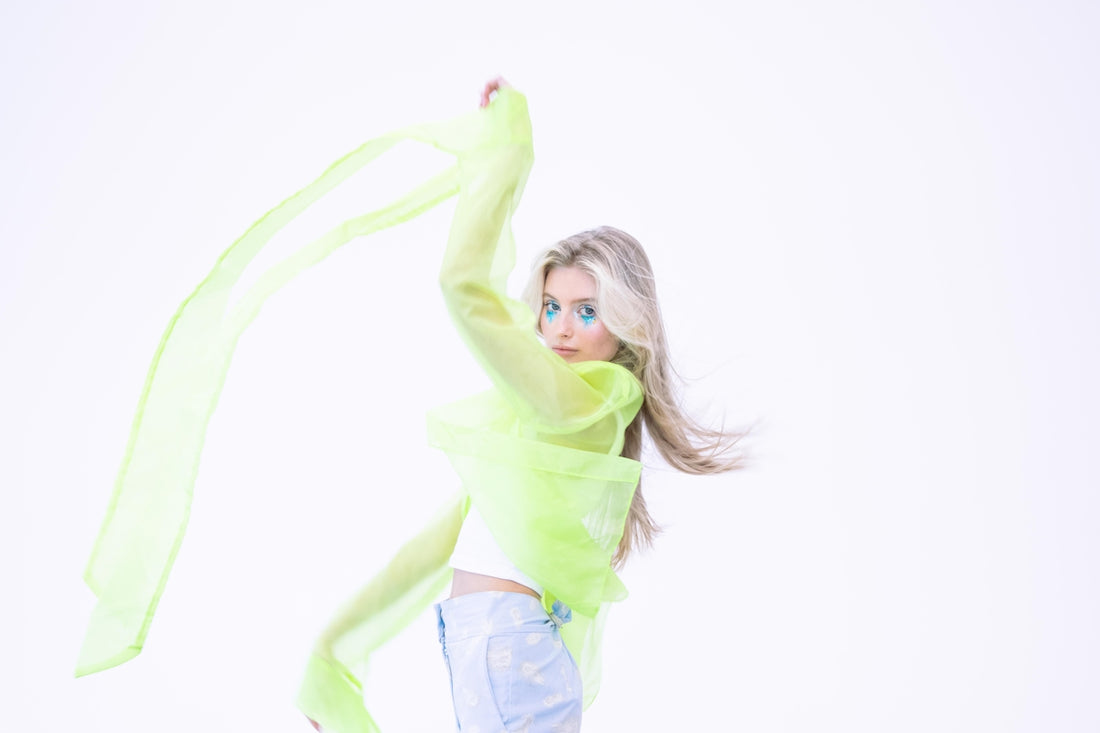 Young woman with flowing green fabric and blue eye makeup.