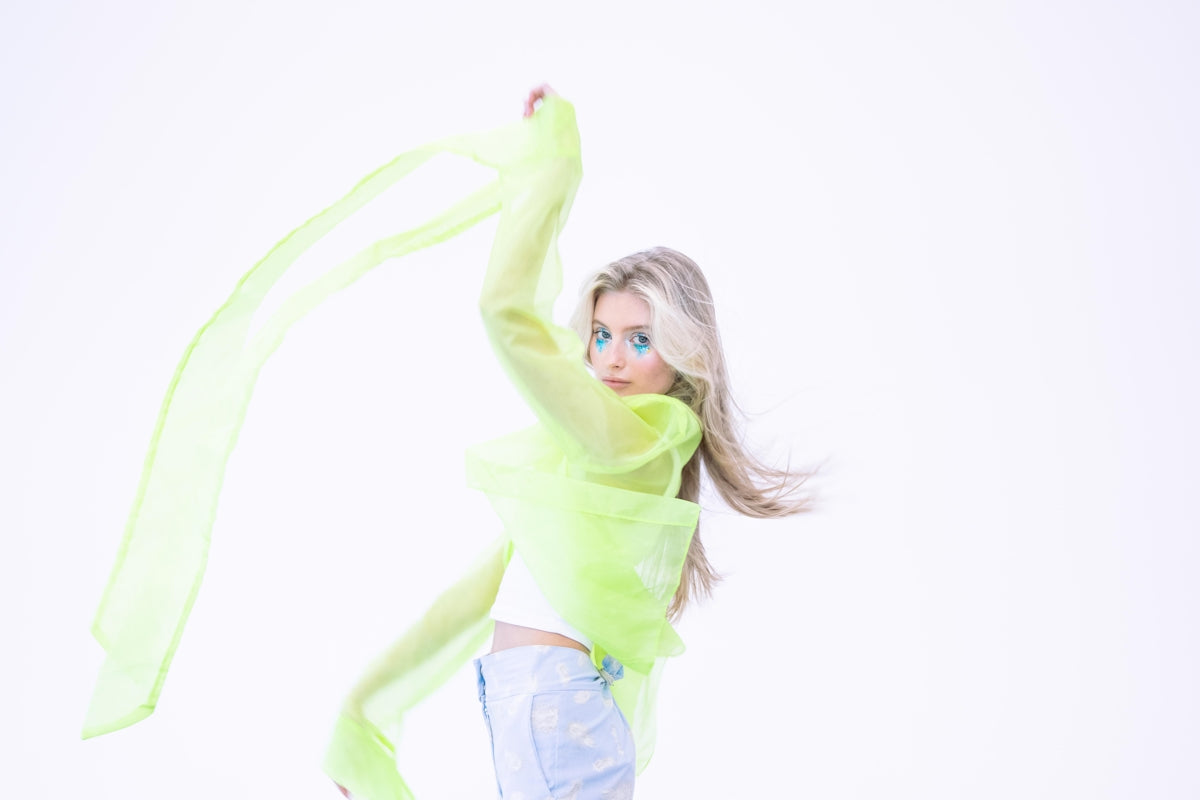 Young woman with flowing green fabric and blue eye makeup.